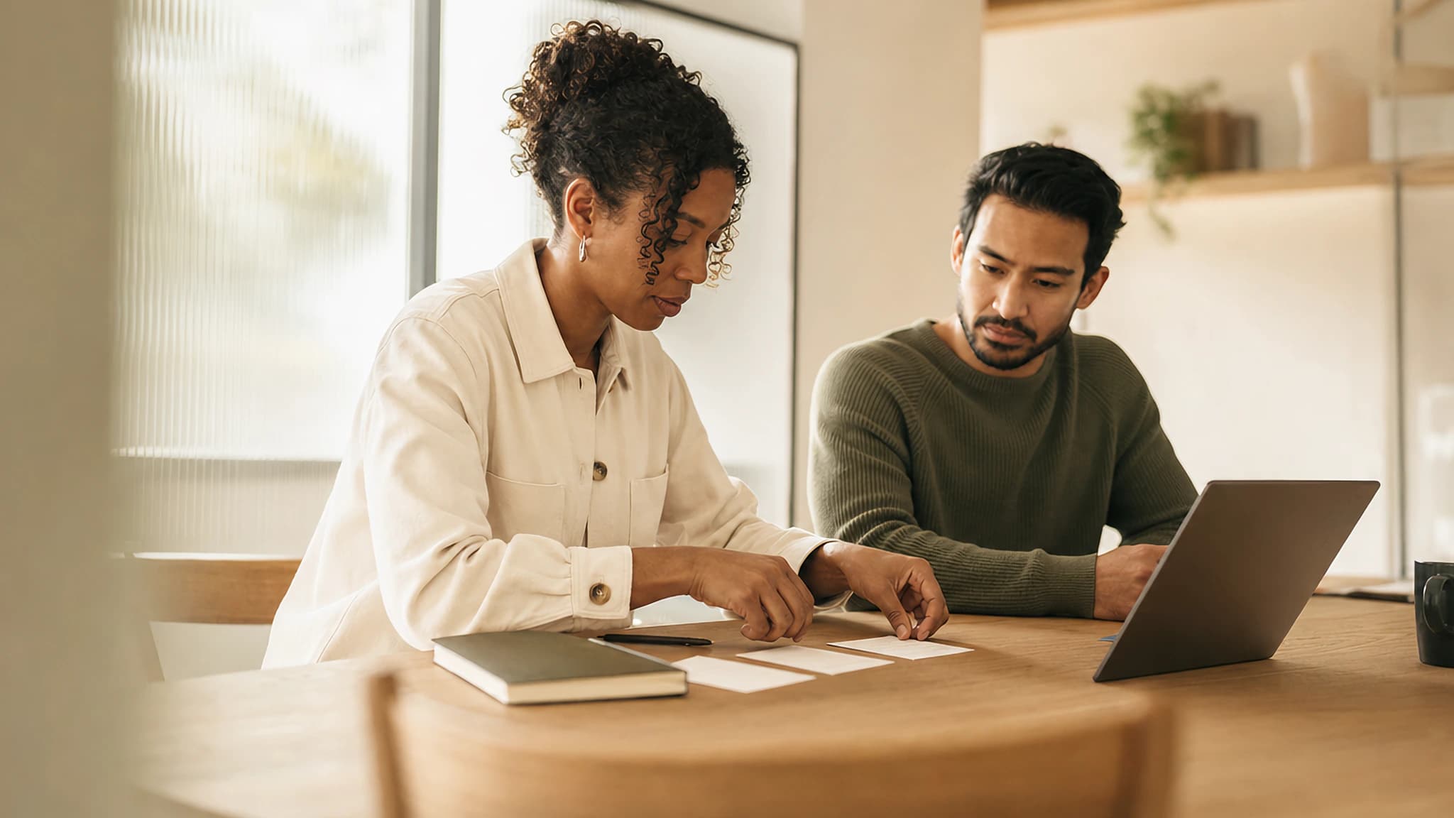A product manager and colleague review launch work and ownership at a shared table.